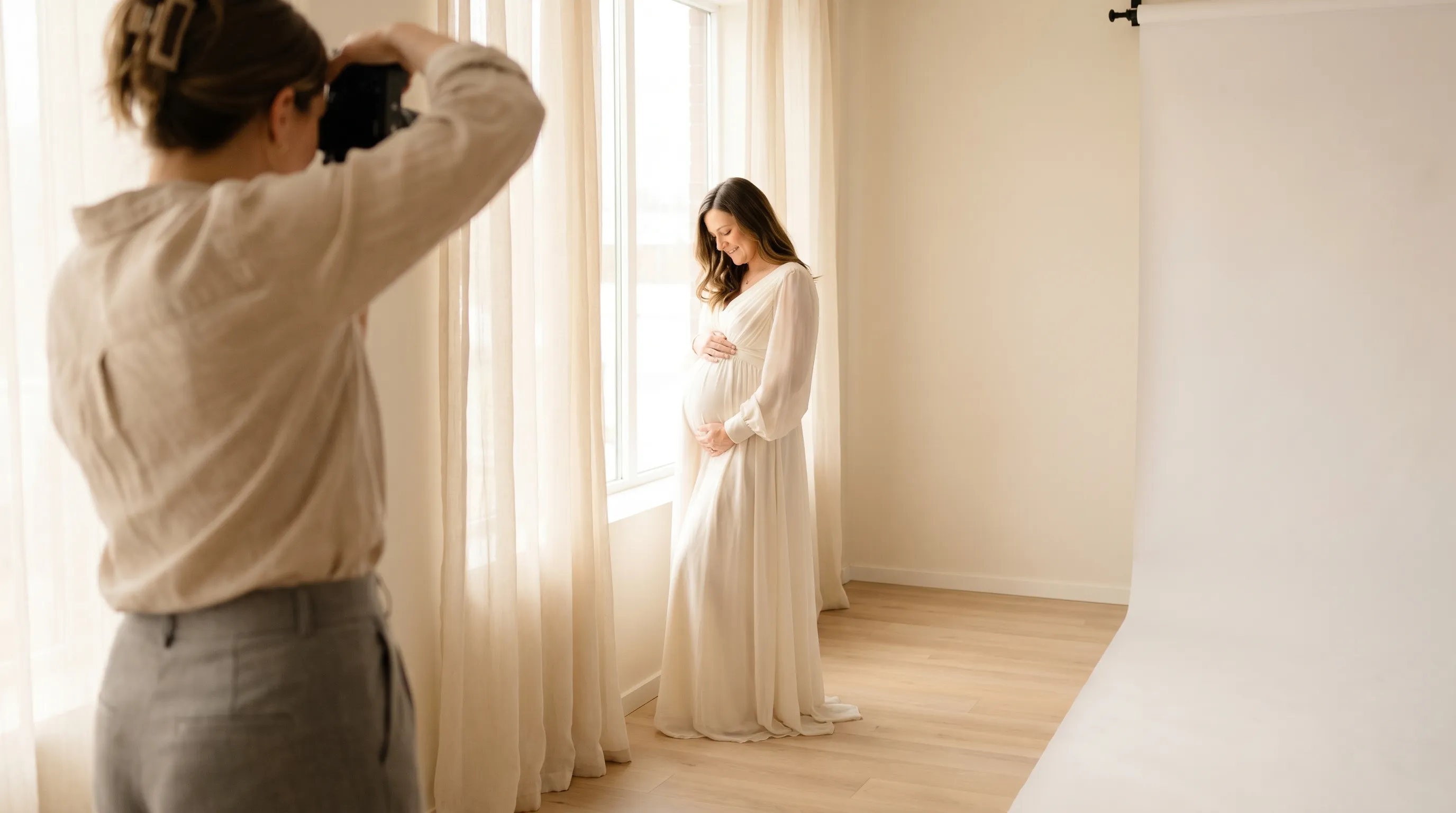 Ședință foto de maternitate într-un studio din Brașov - mamă în trimestrul trei lângă fereastră luminoasă